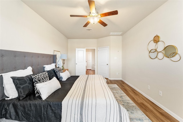 bedroom with wood finished floors, visible vents, baseboards, and ceiling fan