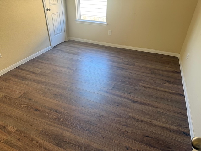 unfurnished room with baseboards and dark wood-style floors