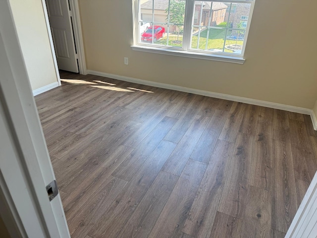 spare room featuring baseboards and dark wood-style floors