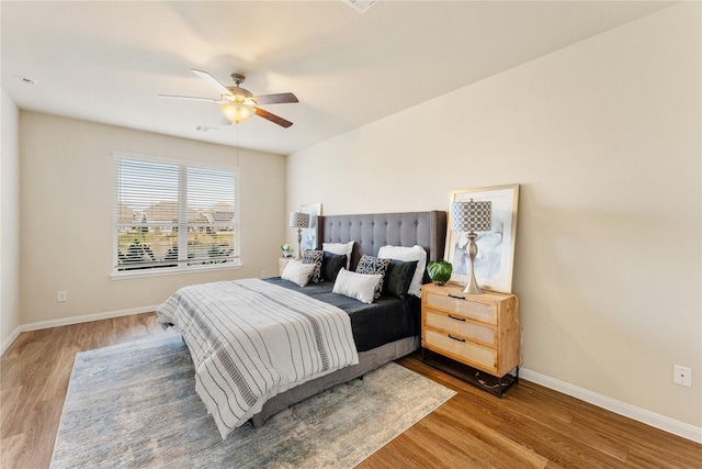 bedroom with wood finished floors, visible vents, baseboards, and ceiling fan