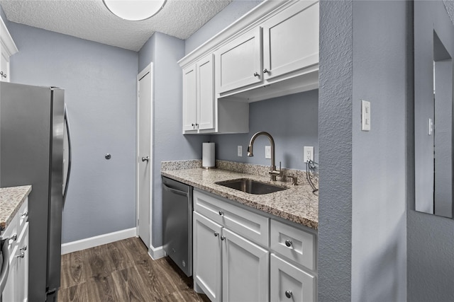 kitchen featuring appliances with stainless steel finishes, light stone countertops, dark wood-style floors, and a sink