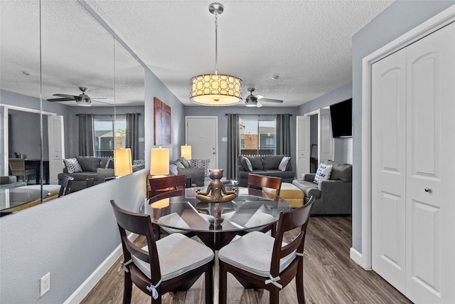 dining area with baseboards, wood finished floors, ceiling fan, and a textured ceiling