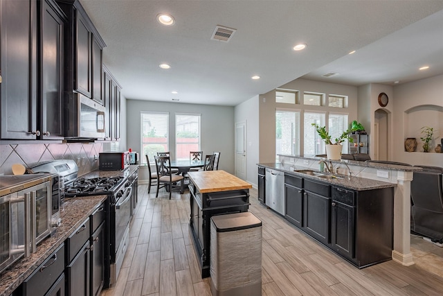 18918 Flintlock Forest Ln, Cypress, TX 77429 - kitchen featuring appliances with stainless steel finishes, dark stone countertops, light wood-style floors, decorative backsplash, and recessed lighting