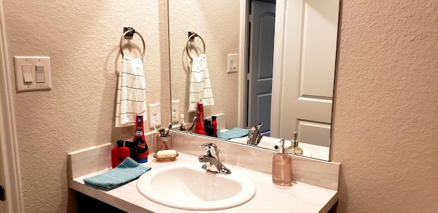 bathroom featuring a textured wall and vanity