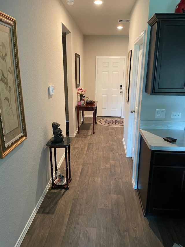 corridor with dark wood-style floors, baseboards, visible vents, and recessed lighting
