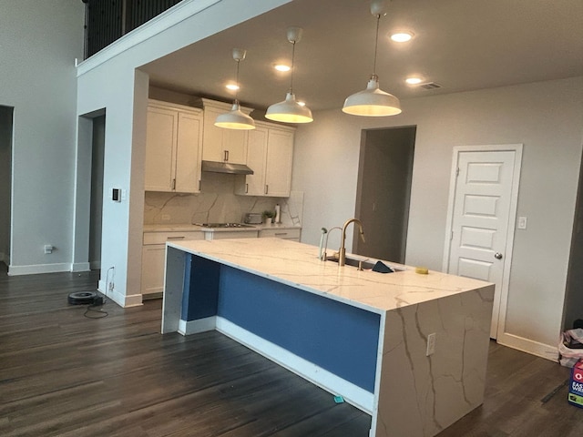 kitchen featuring under cabinet range hood, white cabinetry, a sink, and dark wood-style flooring