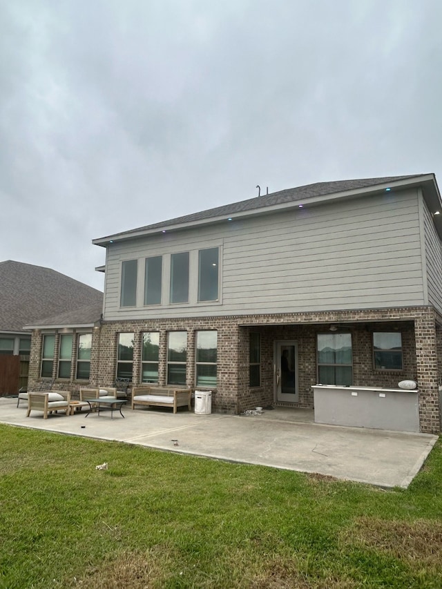 back of property with brick siding, a patio area, and a lawn