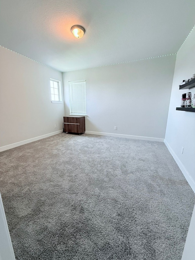 spare room featuring baseboards and carpet