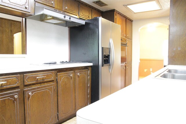 597 County Road 605, Angleton, TX 77515 - kitchen with white stovetop, oven, arched walkways, under cabinet range hood, and visible vents