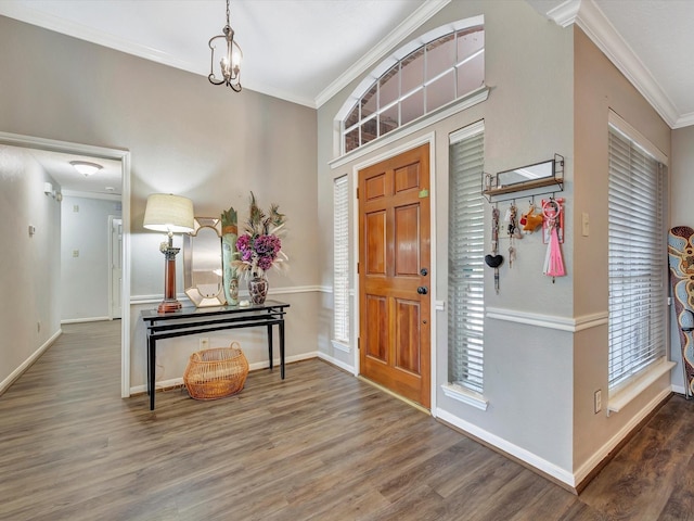 entryway with a chandelier, wood finished floors, baseboards, and ornamental molding
