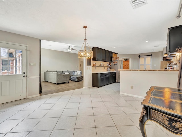 kitchen featuring open floor plan, visible vents, baseboards, freestanding refrigerator, and ceiling fan