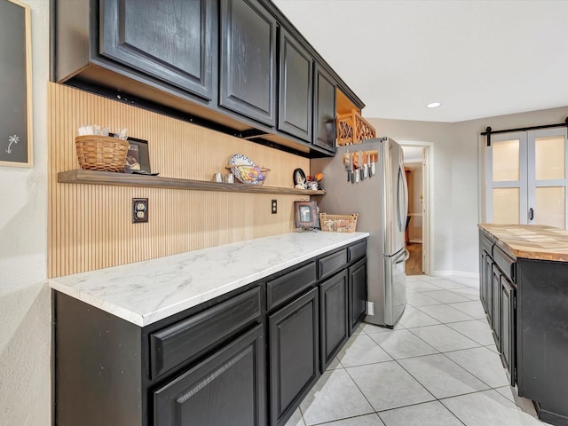 kitchen featuring open shelves, baseboards, freestanding refrigerator, and light tile patterned floors
