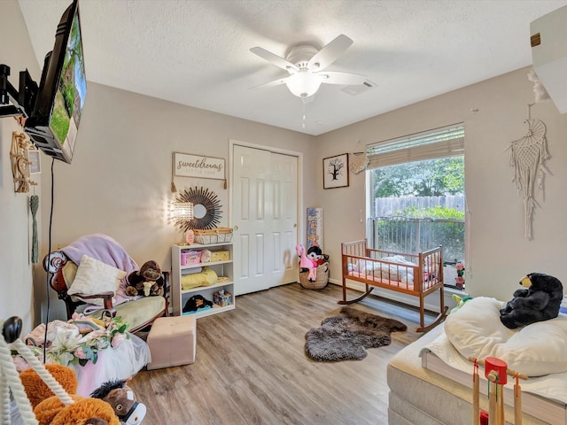 living room featuring visible vents, a ceiling fan, wood finished floors, and a textured ceiling