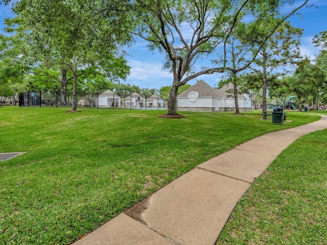 view of community with a lawn and fence