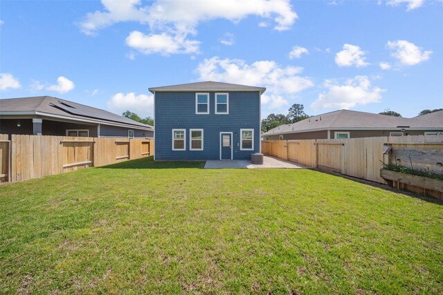 rear view of house featuring a yard, a fenced backyard, and a patio