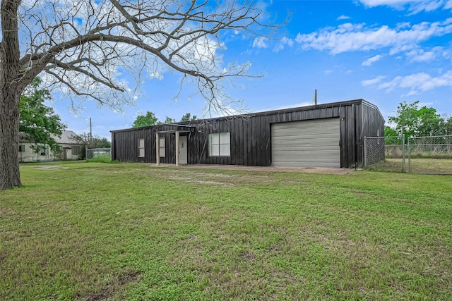 view of outdoor structure featuring fence, an outbuilding, and driveway