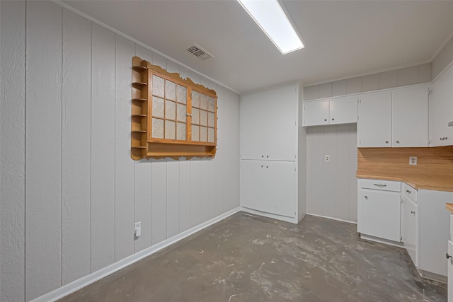 kitchen featuring white cabinets, baseboards, visible vents, light countertops, and unfinished concrete floors