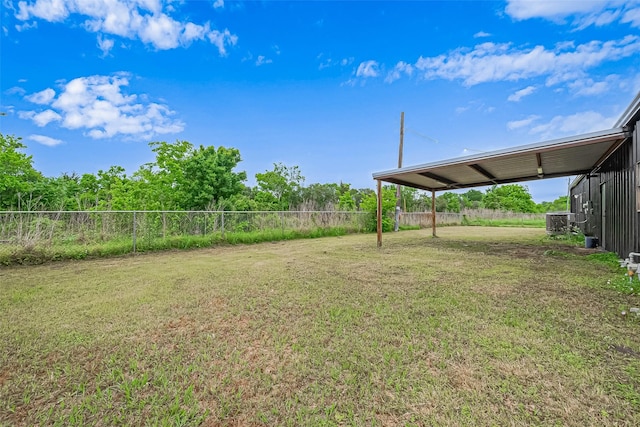 view of yard featuring central AC, a carport, and fence