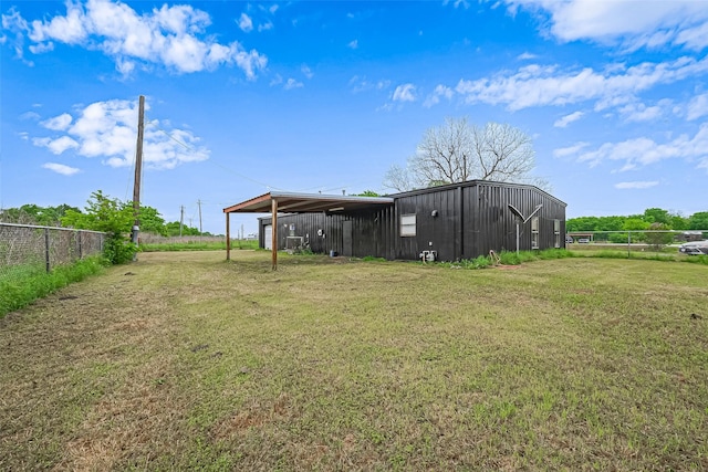 view of yard featuring fence, an outbuilding, a pole building, and a carport