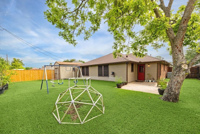 rear view of property with a lawn, a fenced backyard, a patio, and a playground