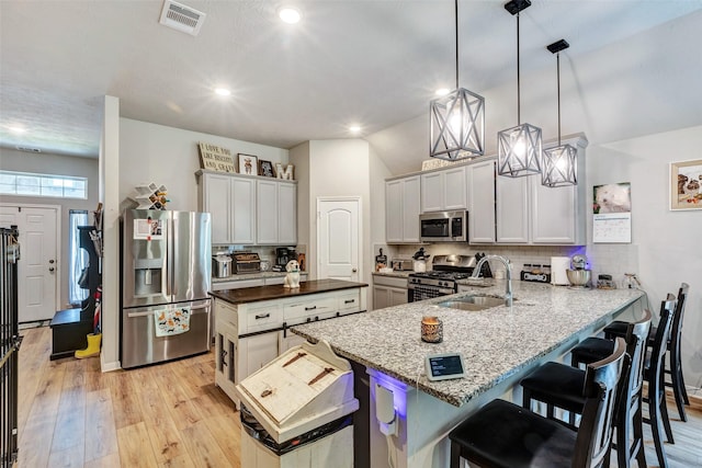108 Alessandra Way, Huntsville, TX 77320 - kitchen featuring a kitchen breakfast bar, decorative backsplash, light wood-style floors, stainless steel appliances, and visible vents