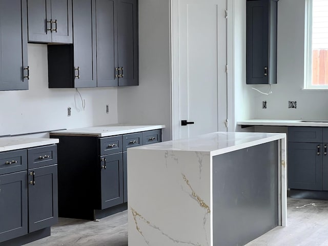 6405 Sidney St, Houston, TX 77021 - kitchen with light wood-style flooring, light stone countertops, a center island, and gray cabinetry