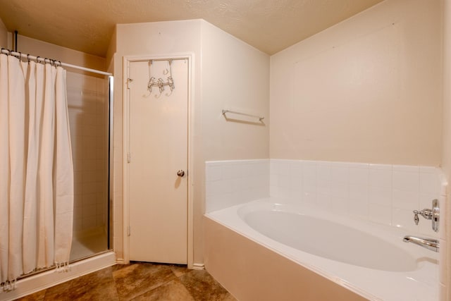 full bathroom featuring a garden tub, a textured ceiling, and a shower stall