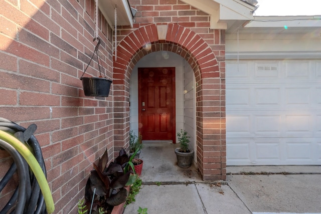 doorway to property featuring brick siding and an attached garage