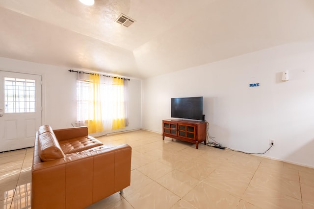 living room featuring vaulted ceiling, visible vents, and light tile patterned floors