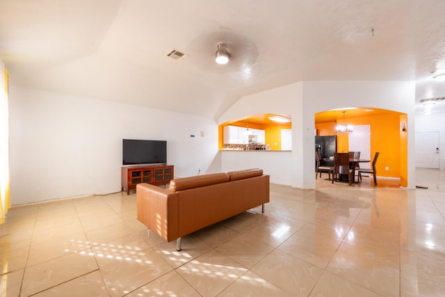 living area featuring arched walkways, vaulted ceiling, visible vents, and light tile patterned floors