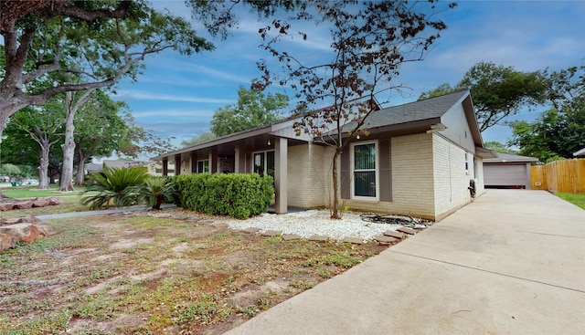 view of front of house with fence, brick siding, roof with shingles, and a detached garage