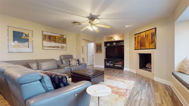 living room with wood finished floors, visible vents, baseboards, a fireplace, and ceiling fan
