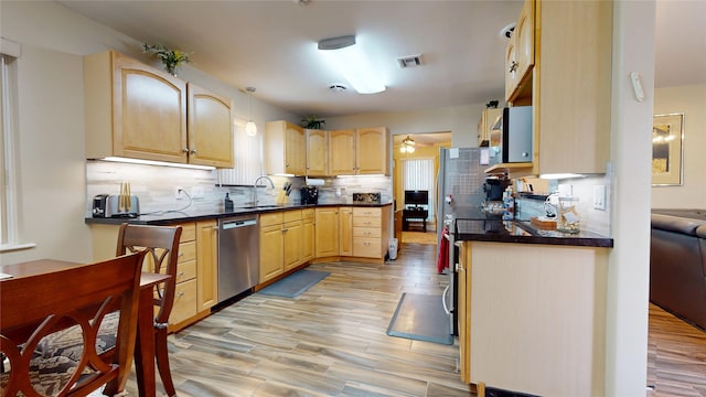 kitchen featuring light brown cabinets, stainless steel dishwasher, tasteful backsplash, and a sink