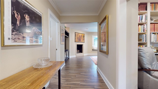 hall featuring wood finished floors, baseboards, and ornamental molding
