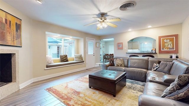 living room featuring a ceiling fan, wood finished floors, a fireplace, visible vents, and recessed lighting