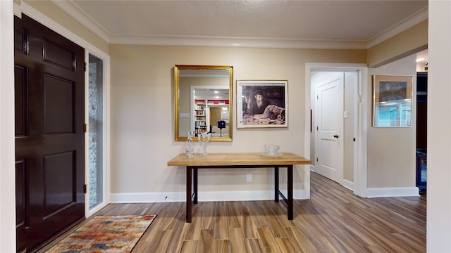 entrance foyer with wood finished floors, crown molding, and baseboards