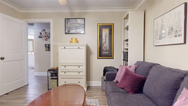 living area with visible vents, light wood-style flooring, baseboards, and ornamental molding