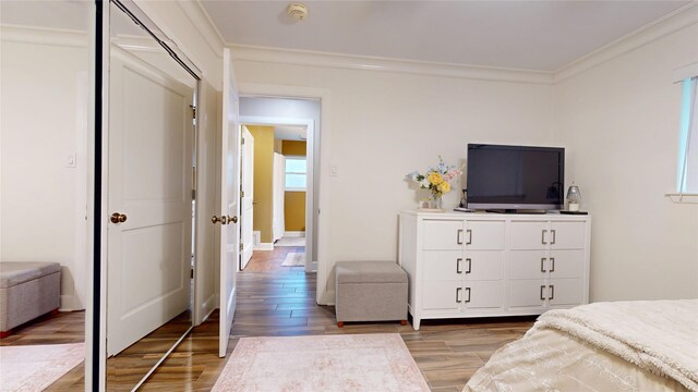 bedroom with light wood-style floors, a closet, and ornamental molding