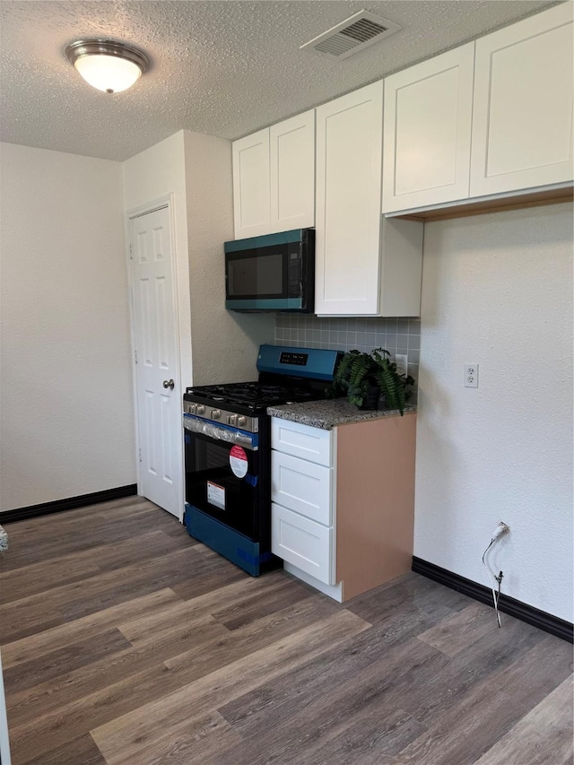 1419 Avenue Ave E, Danbury, TX 77534 - kitchen featuring stainless steel gas range, black microwave, dark wood-type flooring, white cabinets, and a textured ceiling