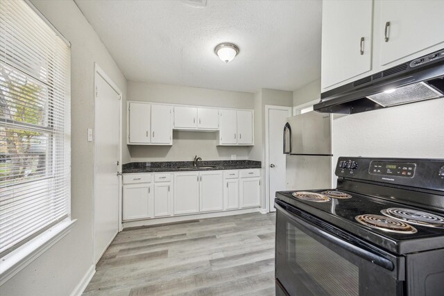 5835 Kenilwood Dr, Houston, TX 77033 - kitchen featuring a sink, black electric range, white cabinetry, under cabinet range hood, and freestanding refrigerator