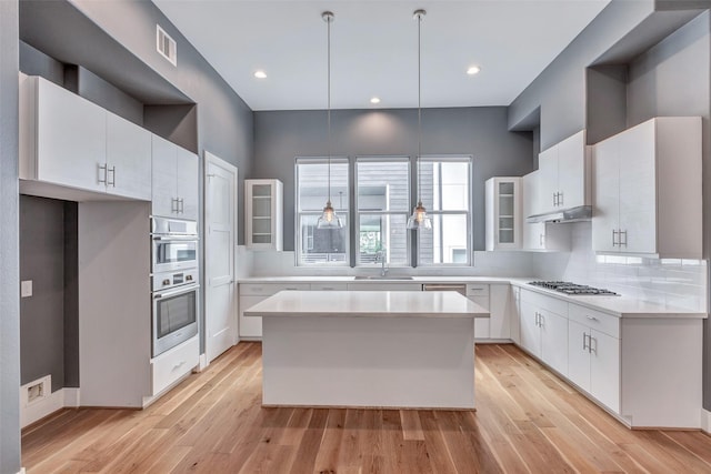 kitchen with white cabinetry, glass insert cabinets, a sink, appliances with stainless steel finishes, and visible vents