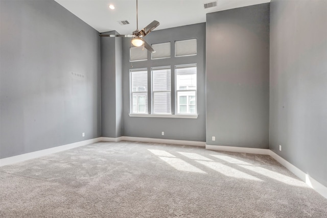 carpeted spare room featuring a ceiling fan, visible vents, and baseboards