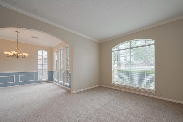 empty room featuring visible vents, crown molding, arched walkways, a chandelier, and carpet flooring