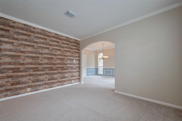 carpeted empty room featuring visible vents, ornamental molding, baseboards, a chandelier, and arched walkways