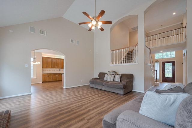 living room featuring ceiling fan, arched walkways, high vaulted ceiling, wood finished floors, and visible vents