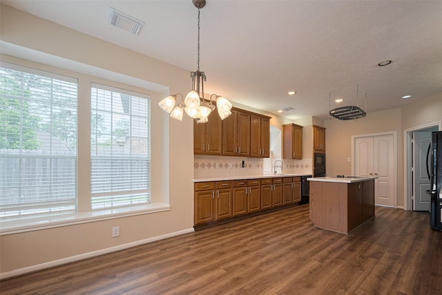 kitchen featuring visible vents, brown cabinetry, plenty of natural light, and black appliances