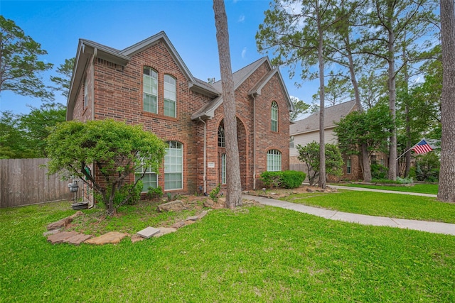 view of front of home with brick siding, a front lawn, and fence