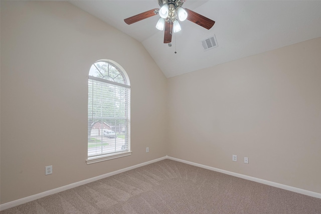 empty room with a ceiling fan, visible vents, light carpet, and vaulted ceiling