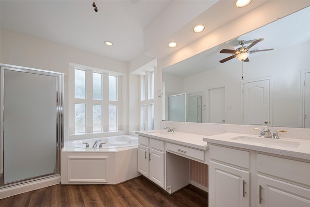 bathroom featuring a bath, a shower stall, wood finished floors, a sink, and recessed lighting