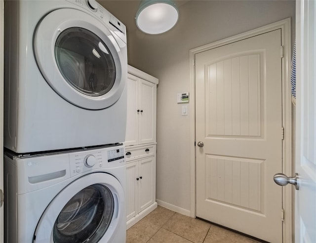 2560 Wild Oak Forest Ln, Seabrook, TX 77586 - laundry room with light tile patterned flooring, stacked washer / drying machine, cabinet space, and baseboards